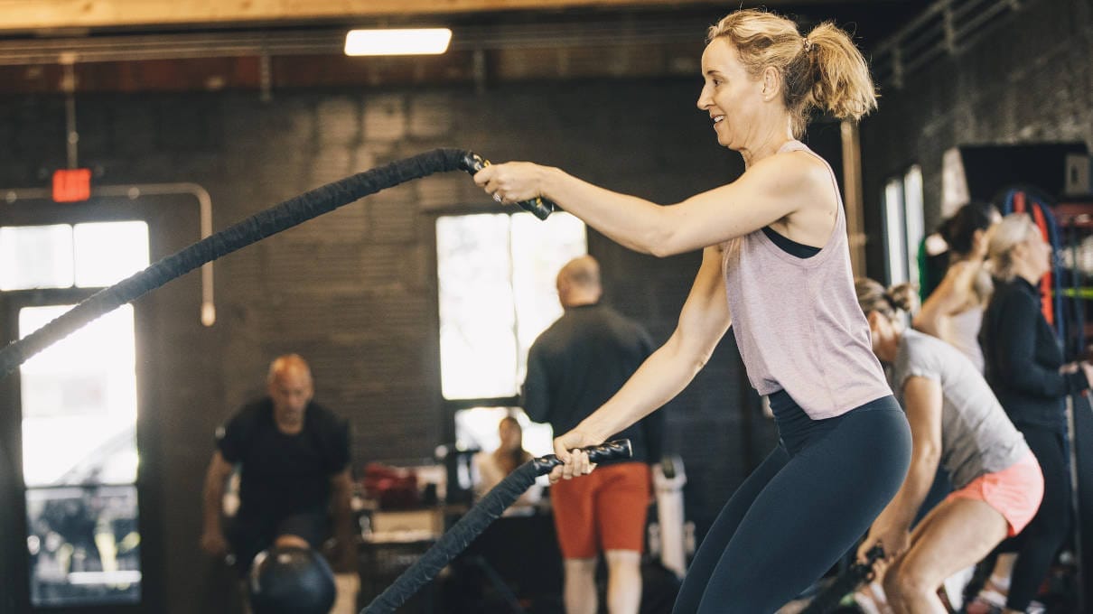 Woman excercising with ropes on small group personal training